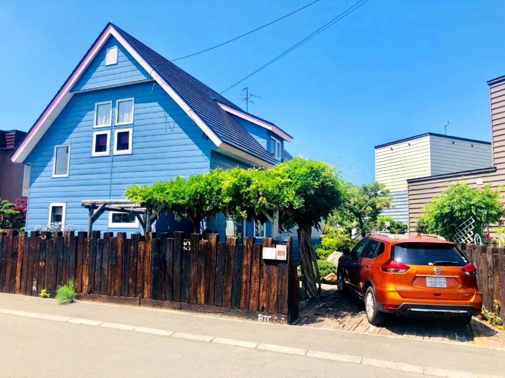 an orange car parked in front of a blue house at Sapporoの実家 B&B Yoshida in Sapporo