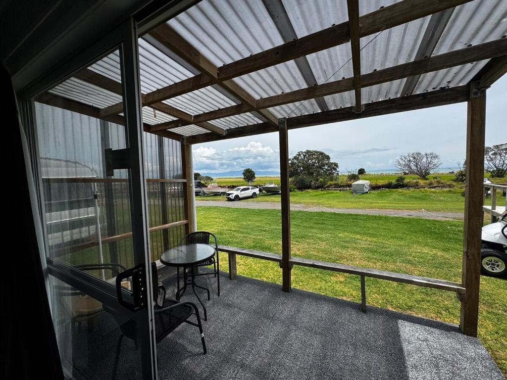 a screened porch with a table and chairs and a view of a field at Seaview Cabin in Tapu