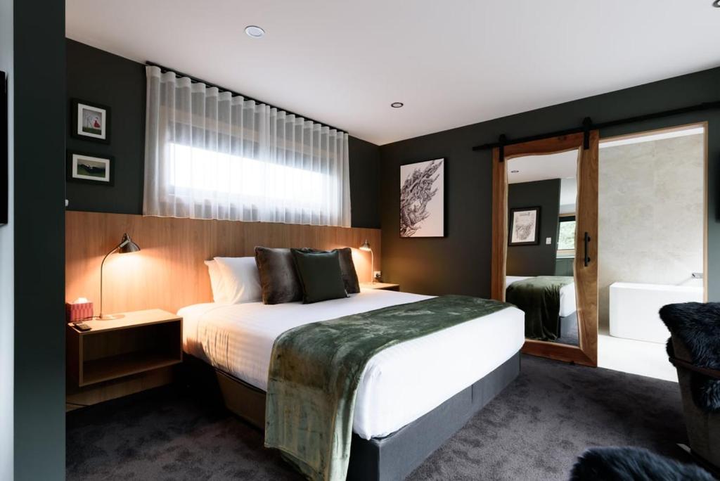 a bedroom with a large bed and a mirror at Moss Wood Lane: Peaceful Bath Hideaway in Spreyton