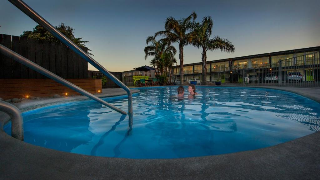 two people are standing in a swimming pool at Aura Accommodation in Rotorua