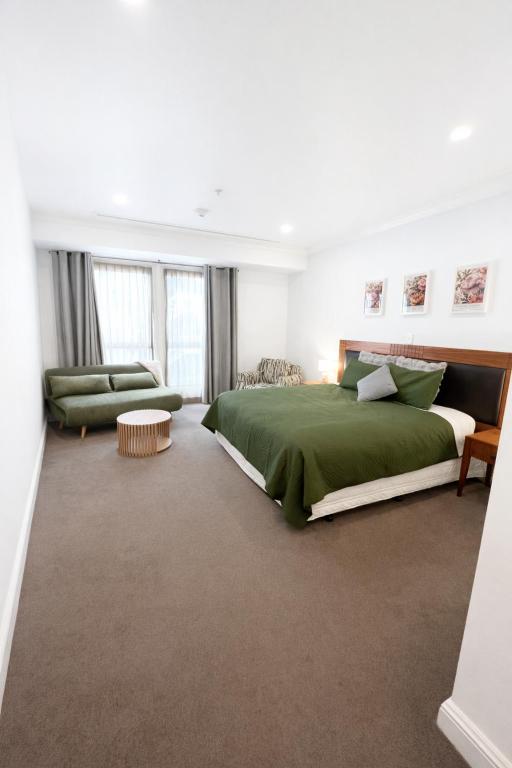 a bedroom with a green bed and a couch at Sky Tower Studio - Pools, Spa, Gym & Super King in Auckland