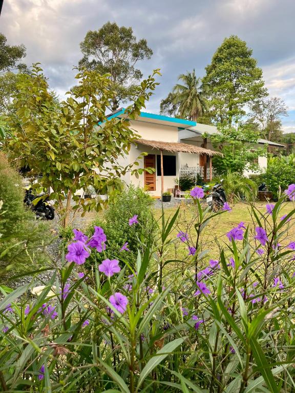 a house with purple flowers in front of it at The Summer Cottage Koh Chang in Khlaung Phai Bae
