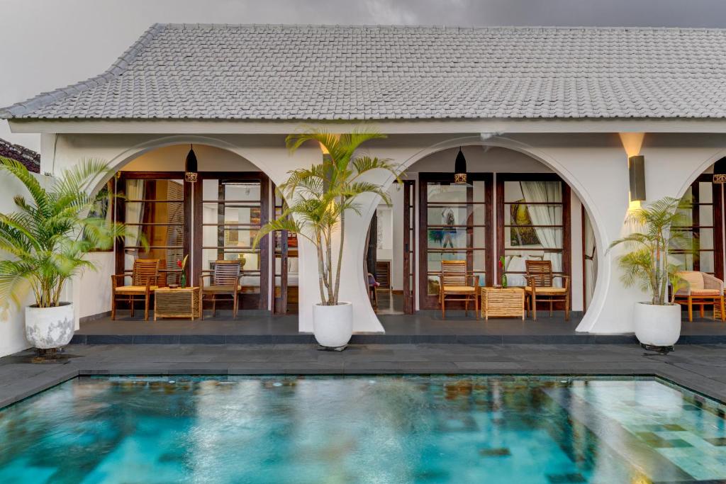 a villa with a swimming pool in front of a house at Olala Suite Canggu Guesthouse in Canggu