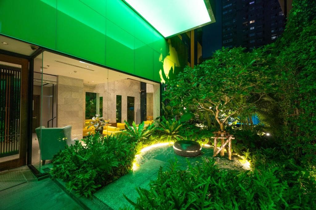 A landscaped entrance garden beside a brightly lit hotel lobby.