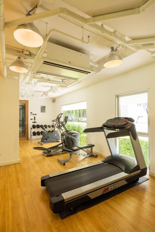 A compact cardio-focused gym with a foreground treadmill, cross-trainers and dumbbells.