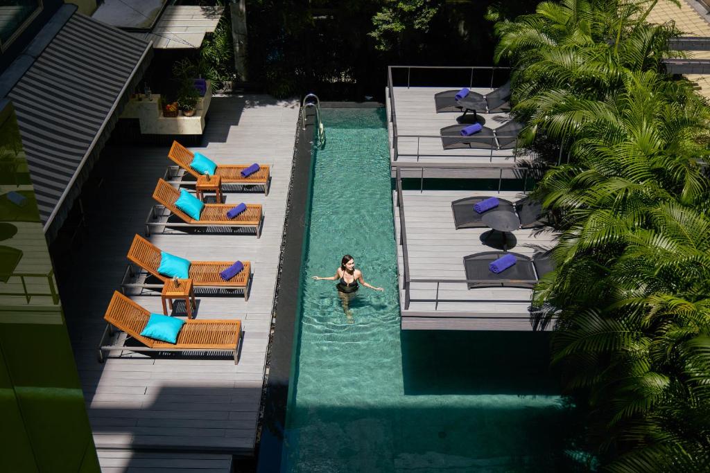 A bird's-eye view of a guest swimming in the narrow pool between two banks of loungers.