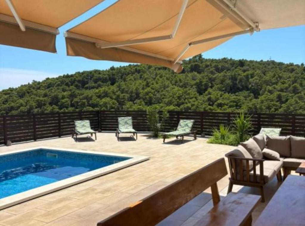 a patio with a swimming pool and an umbrella at Villa Coral in Novo Selo