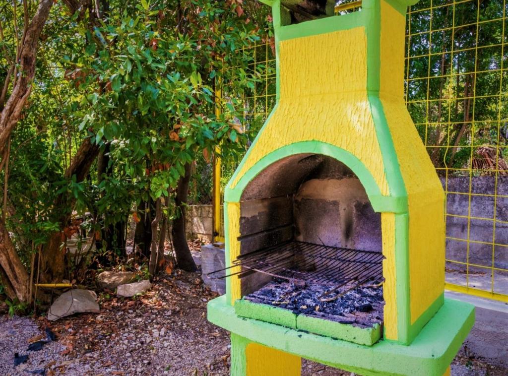 a yellow and green pizza oven in a garden at Nirvana Apartments & Auto Camp in Kumbor