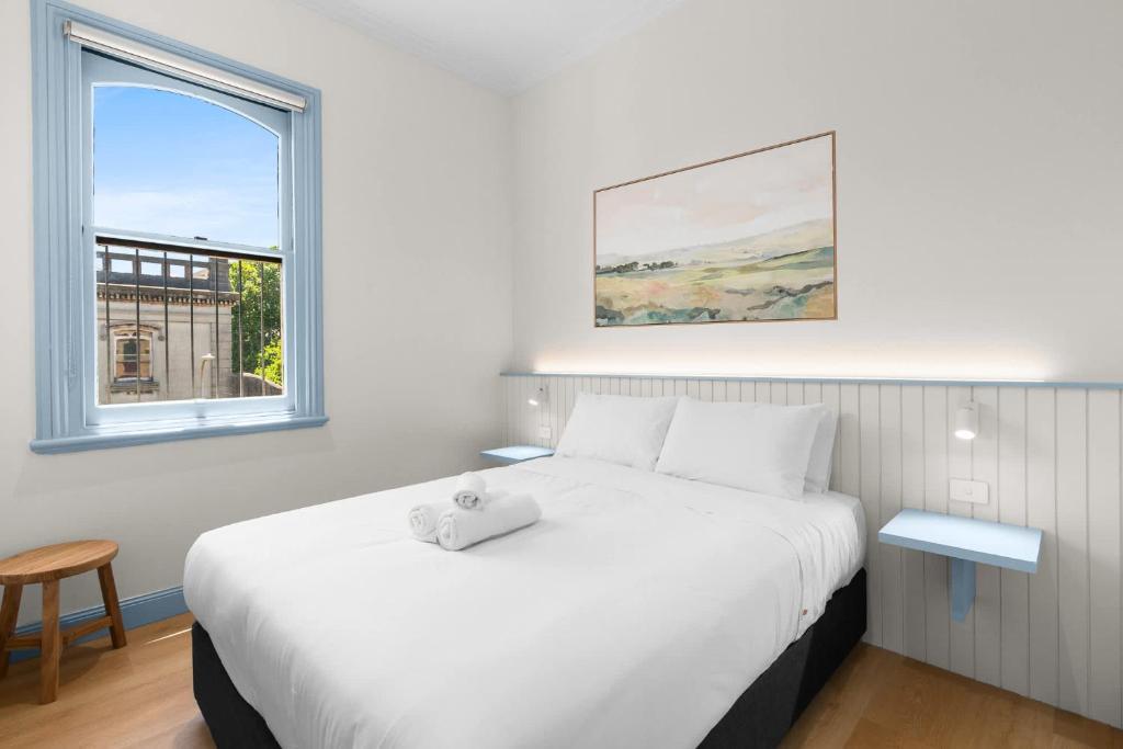 a bedroom with a white bed with a stuffed animal on it at The Surrey 6 in Sydney
