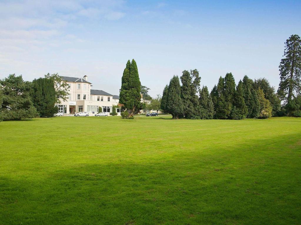 a large green field with a house and trees at Mercure Maidstone Great Danes Hotel in Maidstone