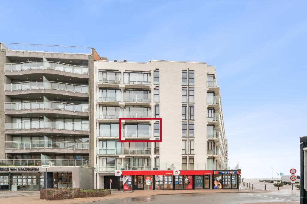 a tall white building with a red window at Hermes P in Sint-Idesbald