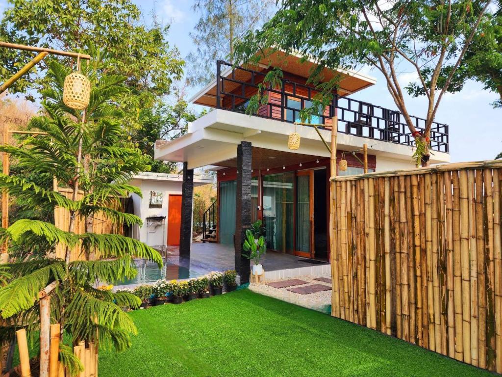 a house with a green lawn in front of it at Phunapat camping Pool villa in Ban Nong Chaeng