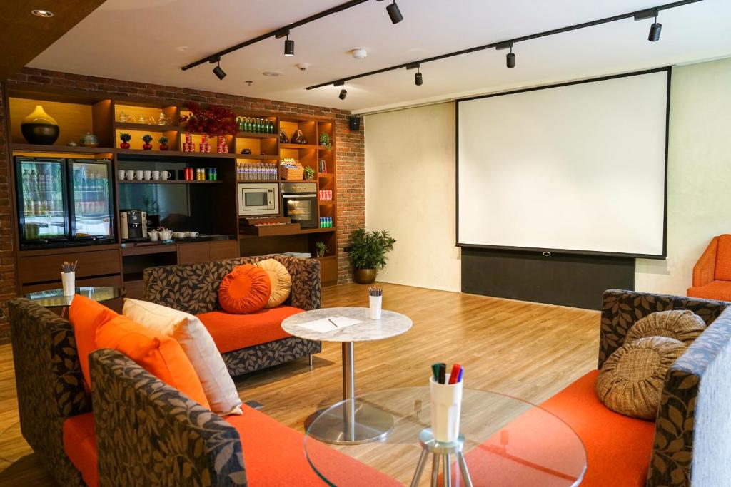 A lounge faces a large projector screen, creating a casual cinema or presentation area.