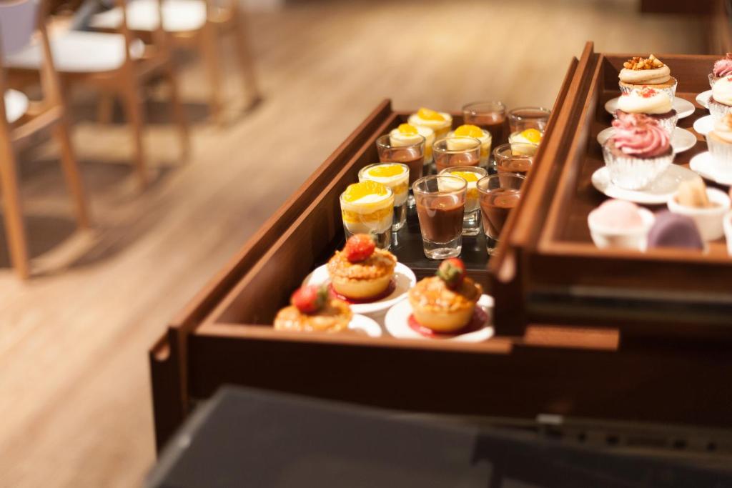 A close-up buffet display presents assorted miniature desserts in wooden trays.