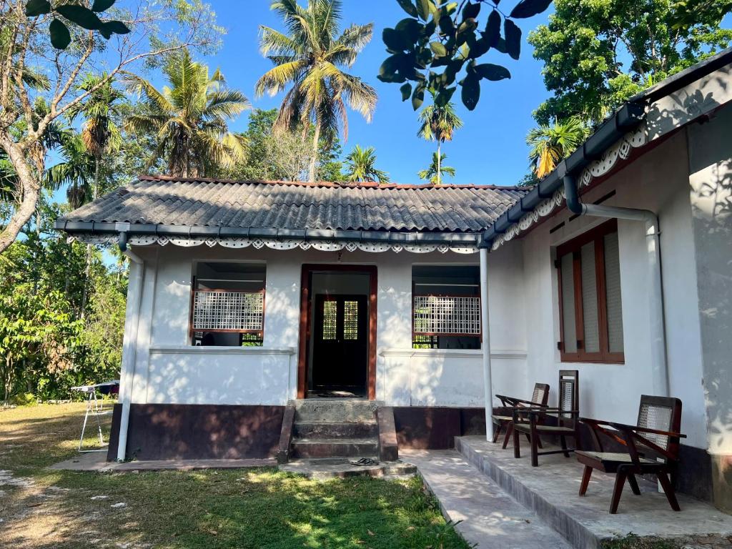 a small white house with a door and chairs at Heritage Eco Garden in Dickwella