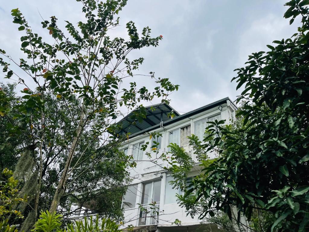 a white house with a solar roof and trees at Grand View Hotel Kandy in Kundasale