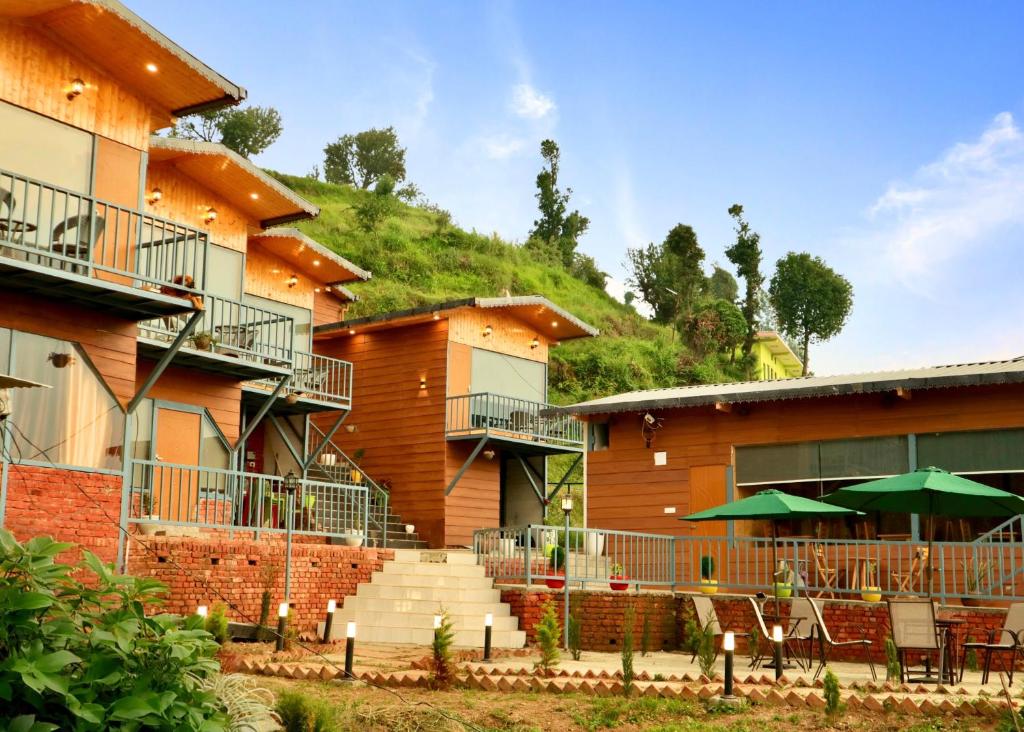 a group of buildings with tables and green umbrellas at The host in Kanatal