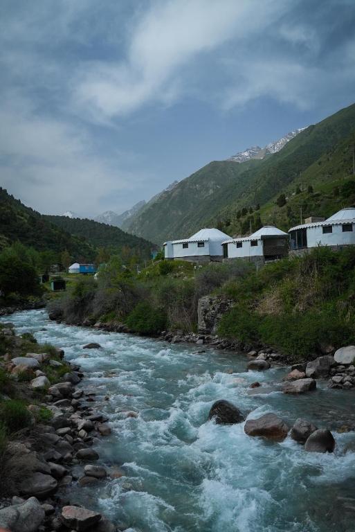 a river with rocks and buildings in the background at RAHMAT yurts in Bishkek