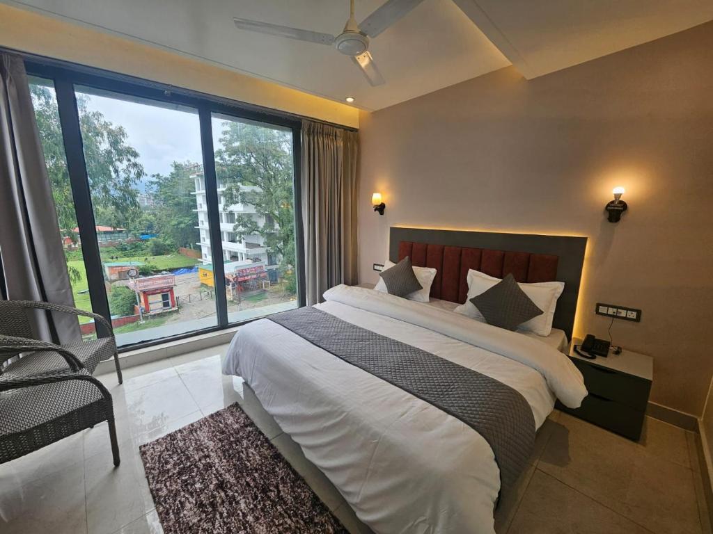 a bedroom with a large bed and a large window at Nirvana Bliss By Cosy Homes, Malsi in Dehradun