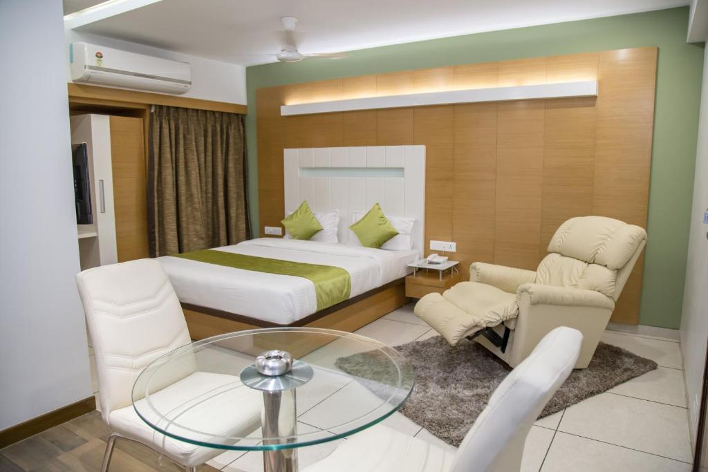 a hotel room with a bed and a glass table at Hotel Orange International in Surat