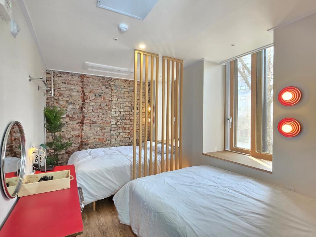 a bedroom with two beds and a brick wall at Quantum Hotel, Seoul Station br in Seoul
