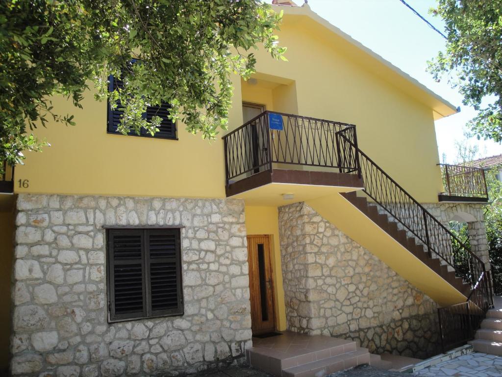 une maison jaune avec un escalier. dans l'établissement Apartments Krešo, à Starigrad-Paklenica