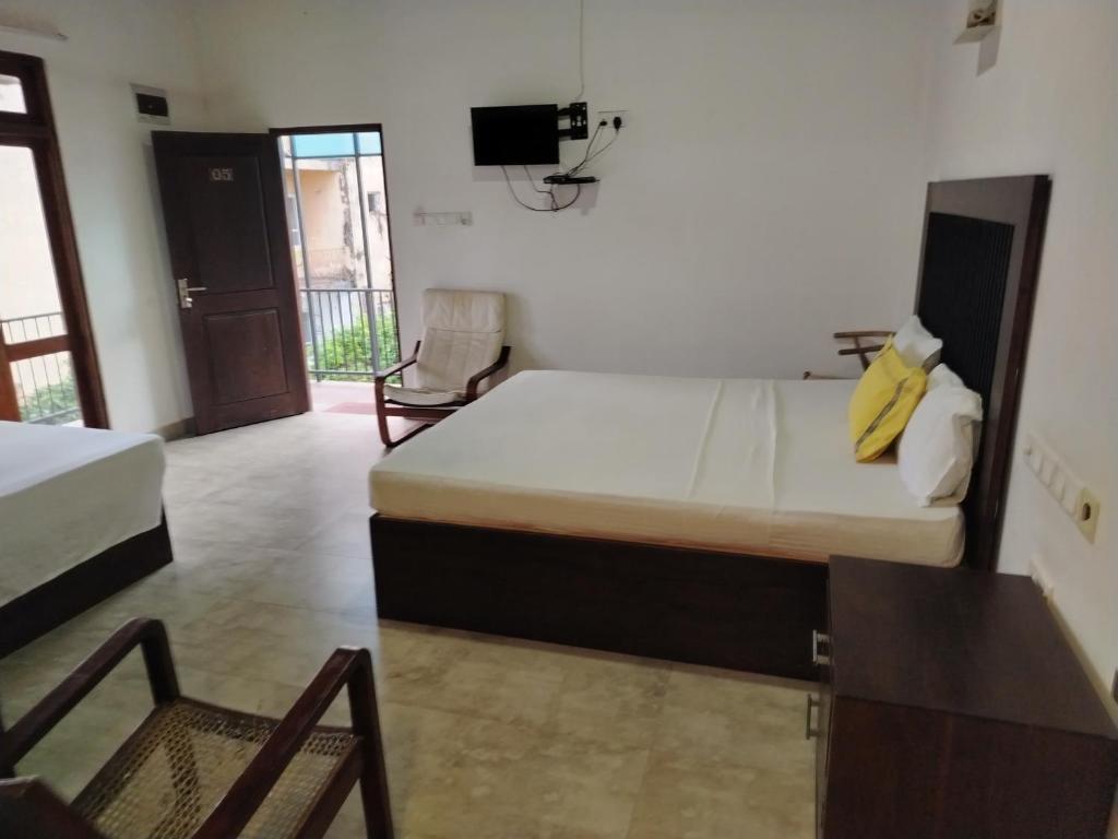 a room with two beds and a tv and a chair at Walker's Residency in Anuradhapura