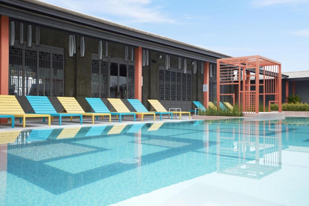 a swimming pool with chairs and a building at The Quarter Hualamphong by UHG in Bangkok