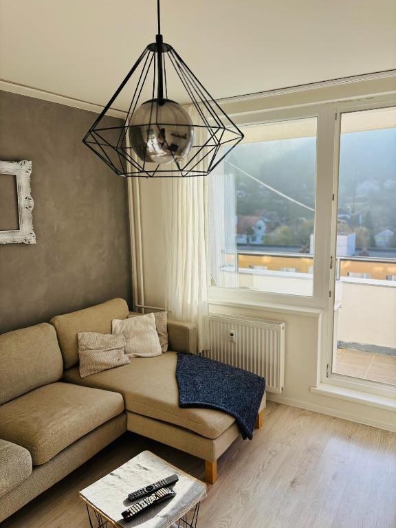 a living room with a couch and a large window at Apartmánový byt VYHNE in Vyhne