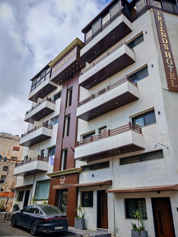 a building with a car parked in front of it at Friends Hotel Jordan in Amman