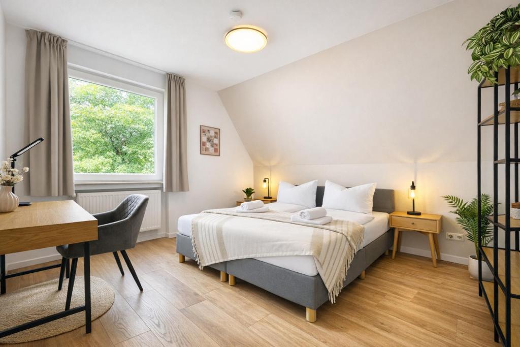 a bedroom with a bed and a desk and a window at Emden City Center - Innenstadt in Emden