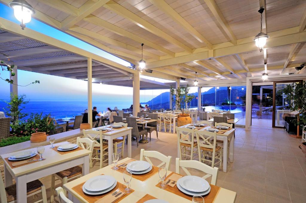 a restaurant with tables and chairs and a view of the ocean at Stefanos Village Hotel in Plakias