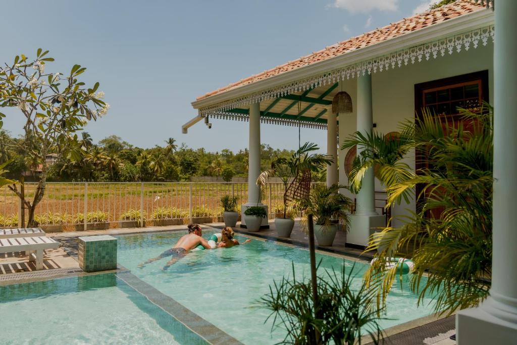 a man and a child playing in a swimming pool at ISOLA - Surf House in Ahangama