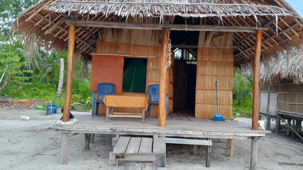 a hut with chairs and a table on the beach at West Waigeo Bungalow in Kabu