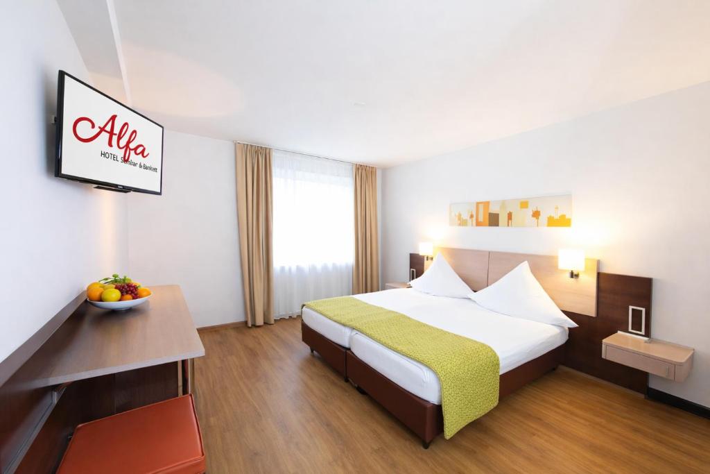 una camera d'albergo con un letto e una ciotola di frutta di Hotel Alfa a Basilea