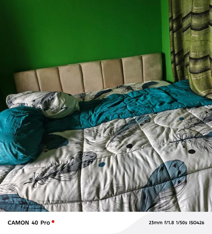 an unmade bed in a bedroom with a green wall at ROYALrest HOTELS in Elele