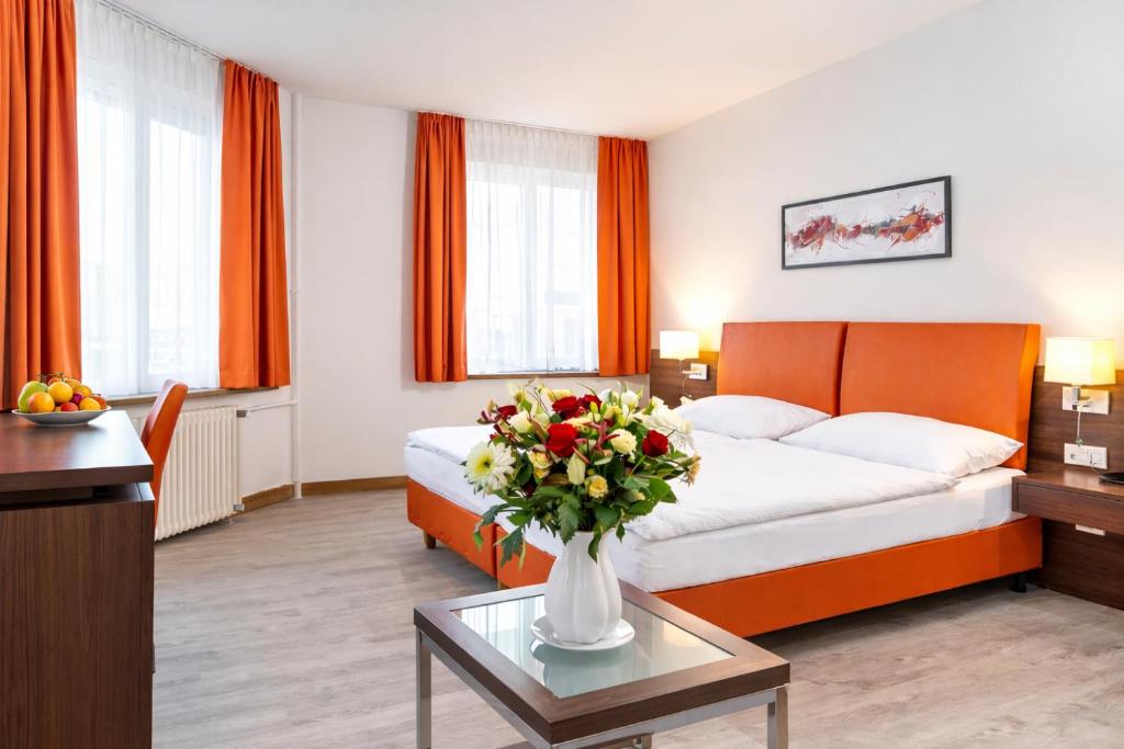 a hotel room with a bed and a vase of flowers at Hotel Rheinfelderhof in Basel