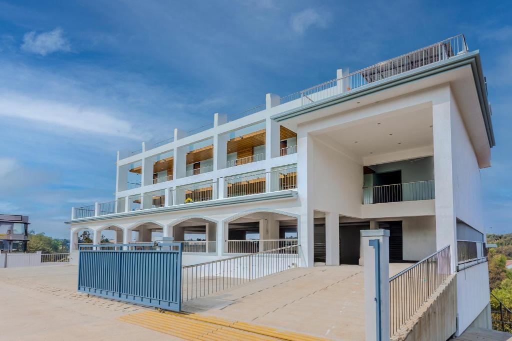 a white building with a blue fence in front of it at ALAYA STAYS Midpoint UMA Pet-Friendly 7 BHK Villa Pool and Entertainment in Chicalim
