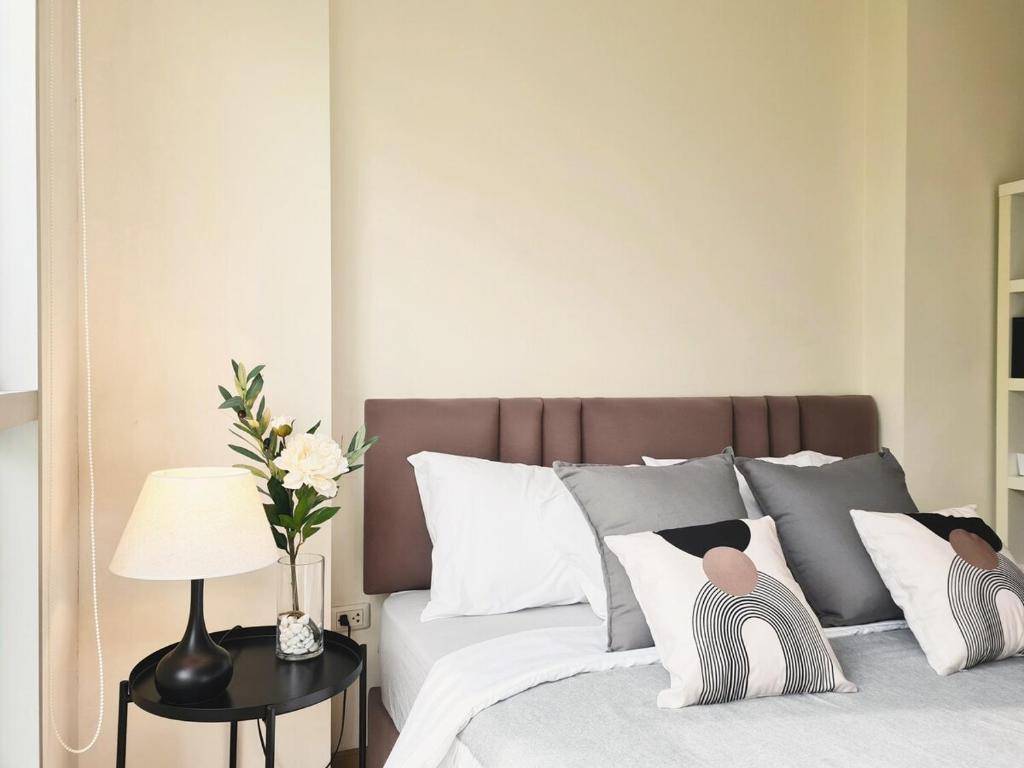 a bed with white pillows and a table with a lamp at Opal in Ban Zong Katiam