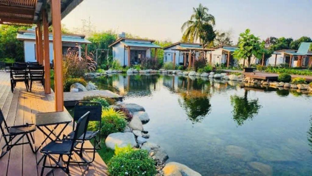 a pond in a yard with chairs and houses at ANORA Homestay in Vũng Liêm