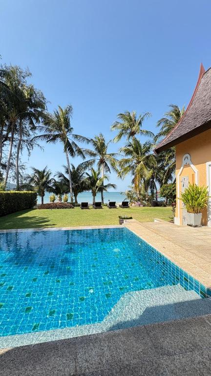 a swimming pool in front of a house with palm trees at Beachfront Pool Villa in Ko Chang