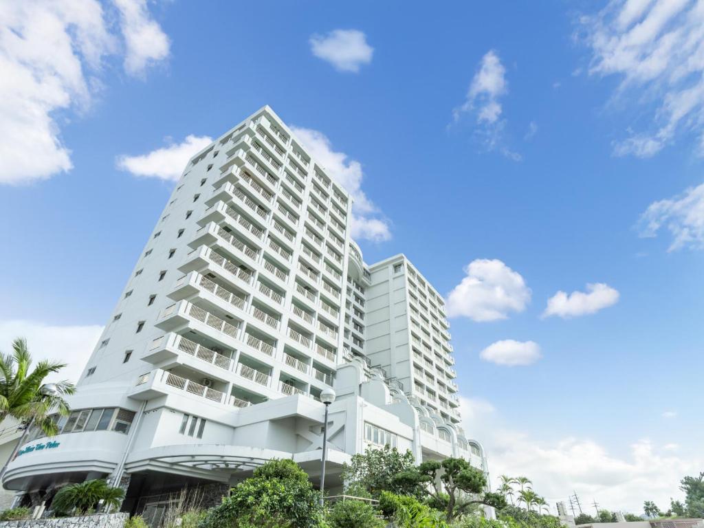 a tall white building with a blue sky in the background at 恩納マリンビューパレス in Onna