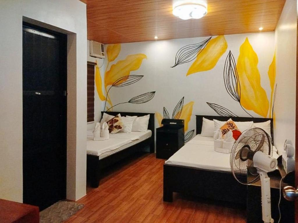a room with two beds with yellow leaves on the wall at RedDoorz at Balai Malinawon Siargao in General Luna