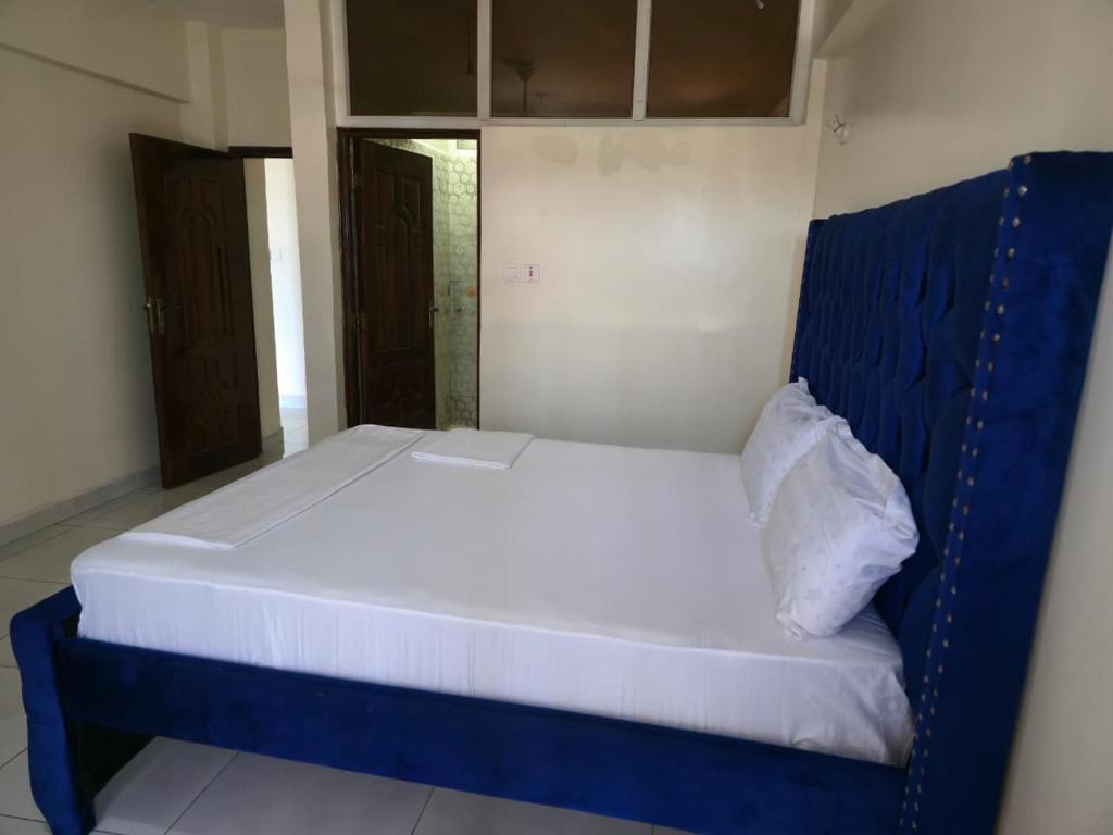 a bed with a blue headboard in a room at Darwin Homes in Mombasa