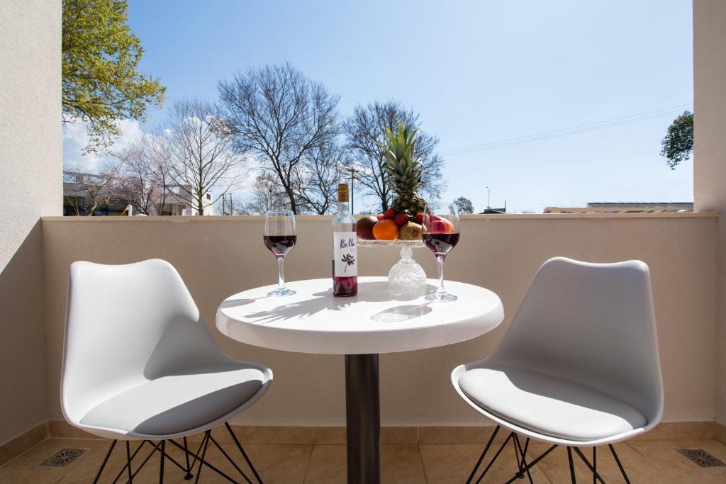 a table with two chairs and two glasses of wine at Veneti Apartments - Corfu Serene Getaways in Sidari