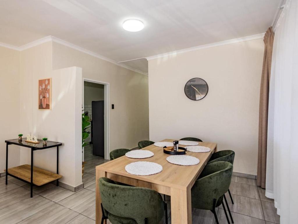 a dining room with a wooden table and green chairs at Olive House in Brackenfell