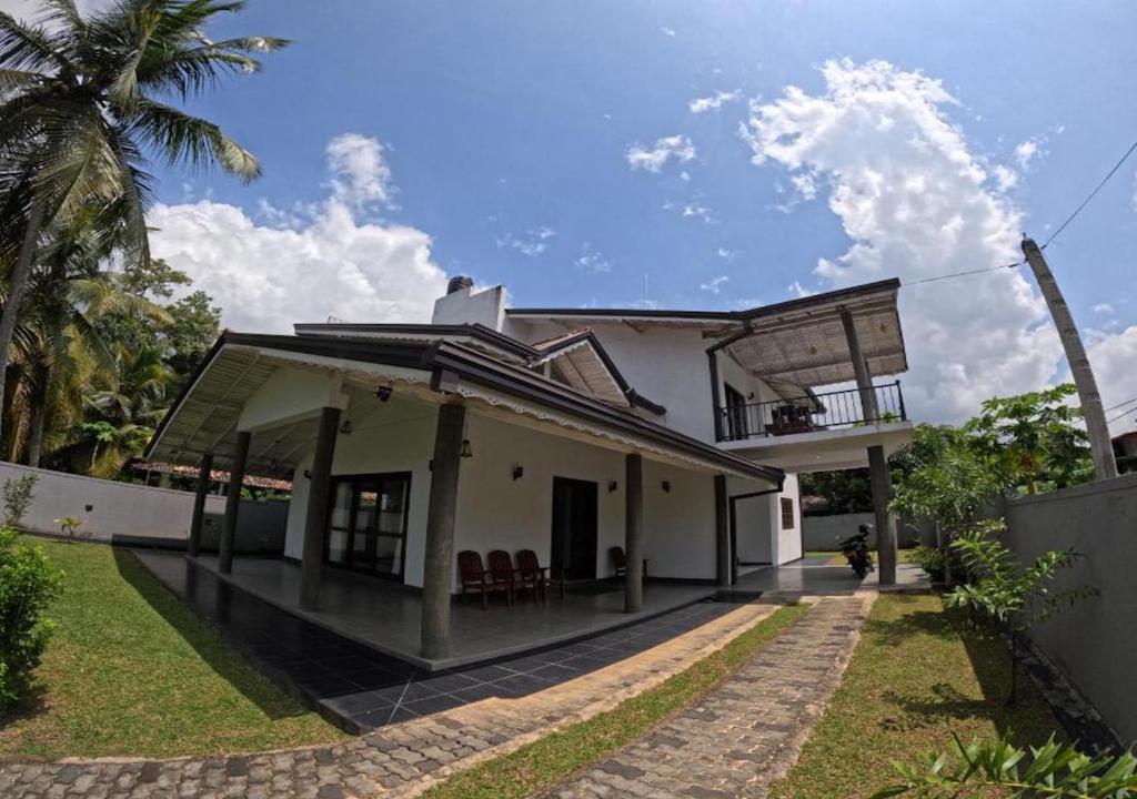 a white house with a porch and chairs on it at Shade Villa in Galle