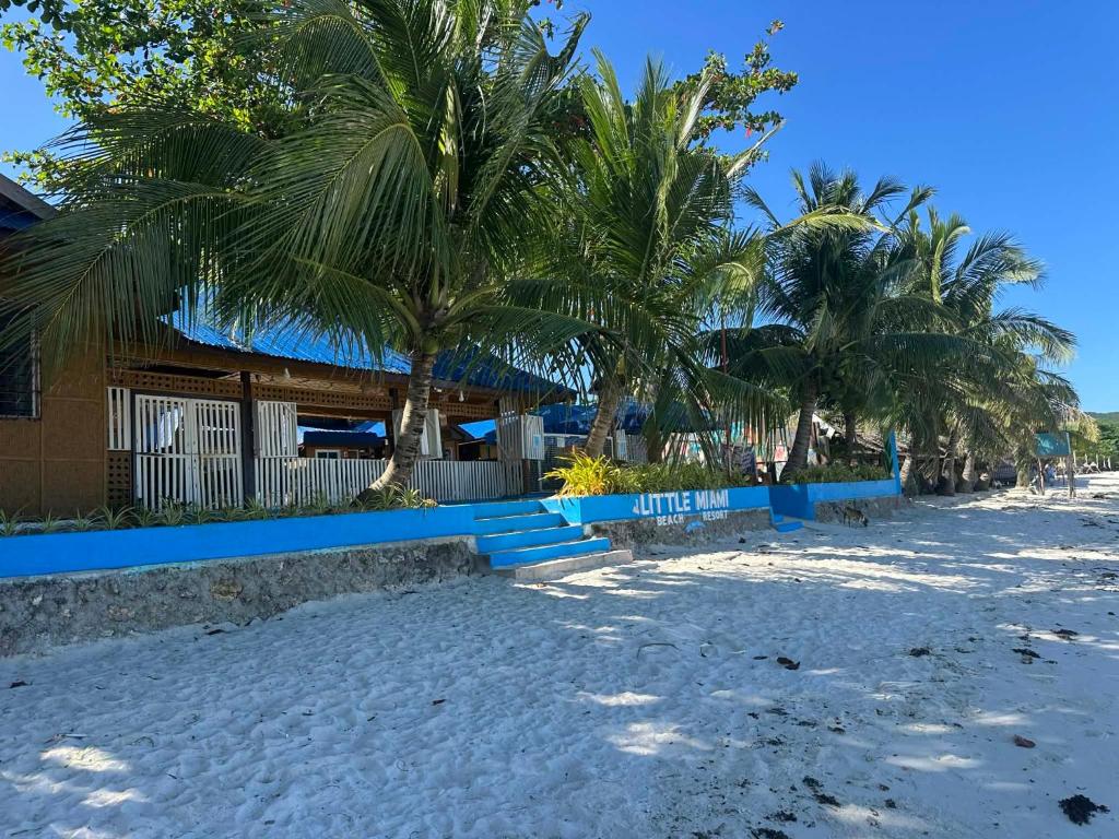 a beach with palm trees and a building at Little Miami Beach Resort in Anda