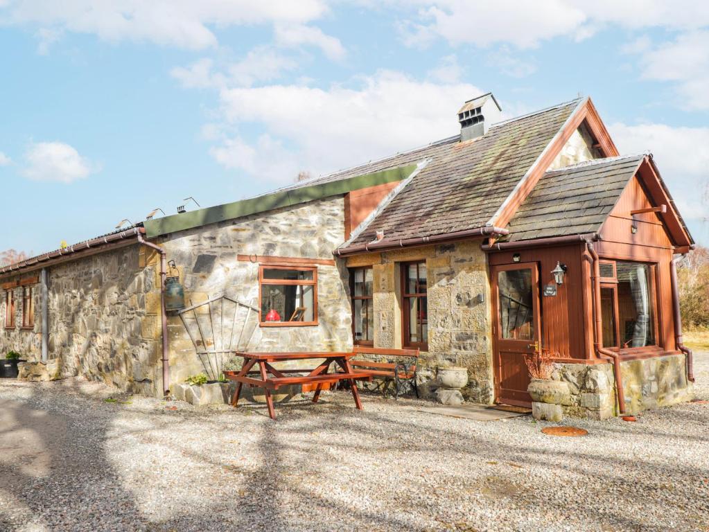 a stone house with a picnic table in front of it at Islay Cottage in Kincraig