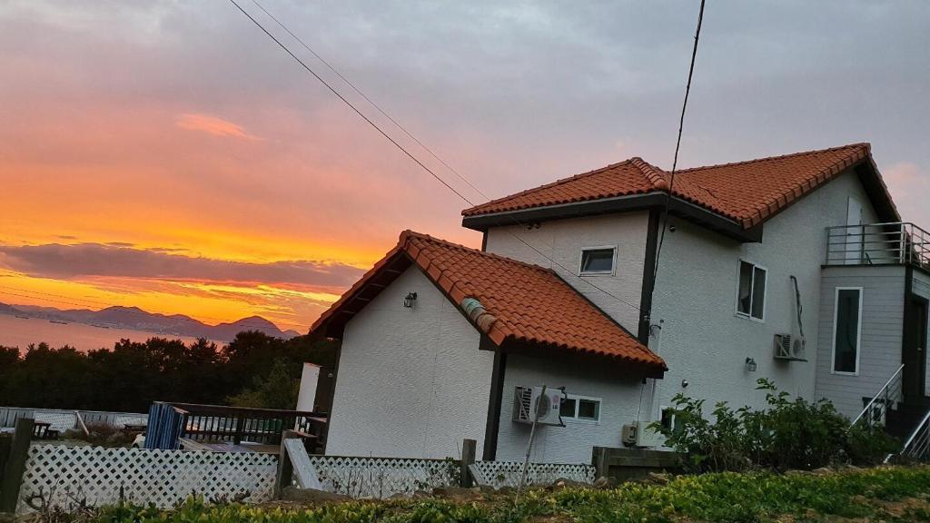 a house with a sunset in the background at Namhae Tovhouse Pension in Namhae